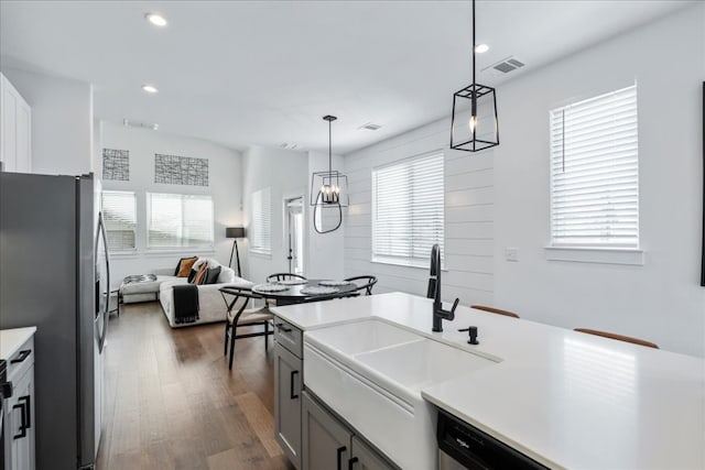 kitchen featuring gray cabinetry, pendant lighting, dark wood-type flooring, stainless steel refrigerator, and sink