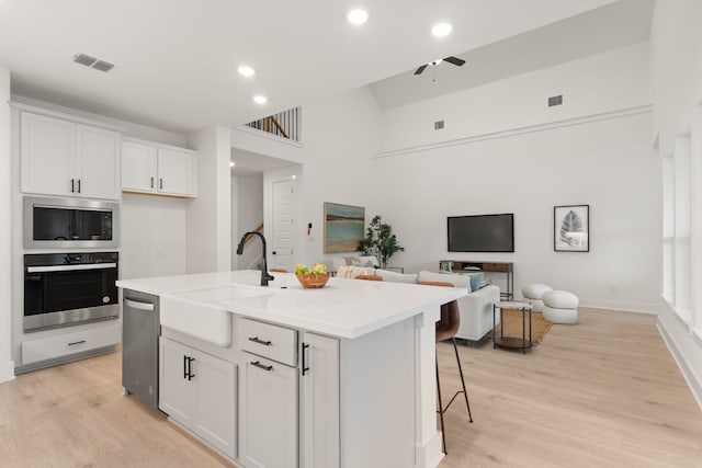 kitchen with appliances with stainless steel finishes, sink, a kitchen island with sink, and white cabinets