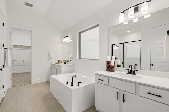 bathroom with independent shower and bath, vaulted ceiling, and vanity