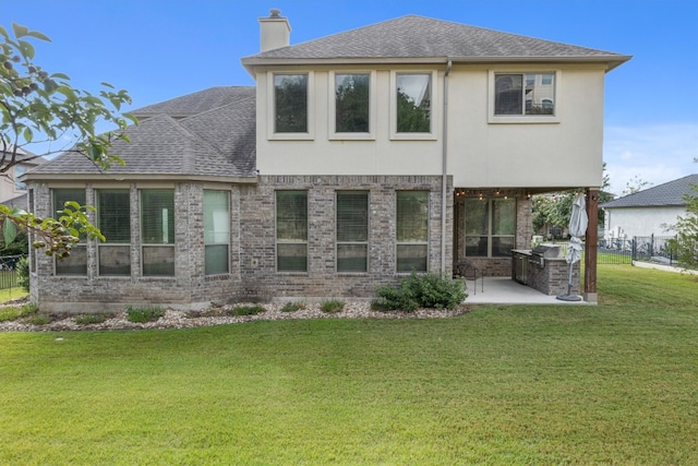 rear view of house with an outdoor kitchen, a yard, and a patio area