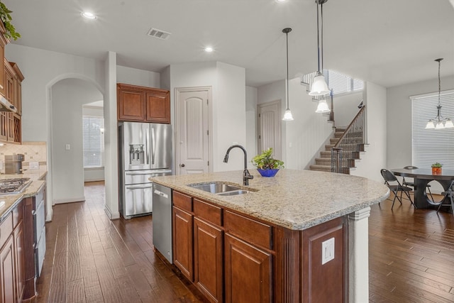 kitchen featuring appliances with stainless steel finishes, sink, dark wood-type flooring, and an island with sink