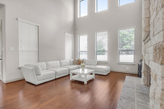 living room featuring a stone fireplace and dark hardwood / wood-style floors