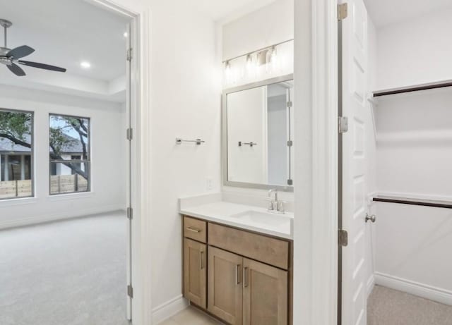 bathroom with a raised ceiling, vanity, and ceiling fan