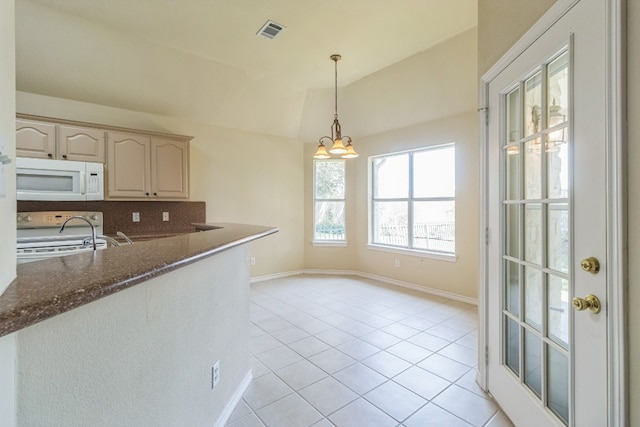 kitchen with a chandelier, lofted ceiling, stove, light tile patterned floors, and dark stone countertops