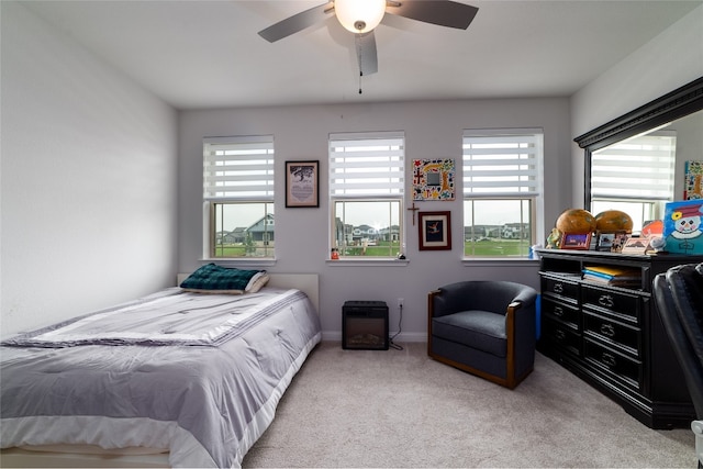 carpeted bedroom featuring multiple windows and ceiling fan