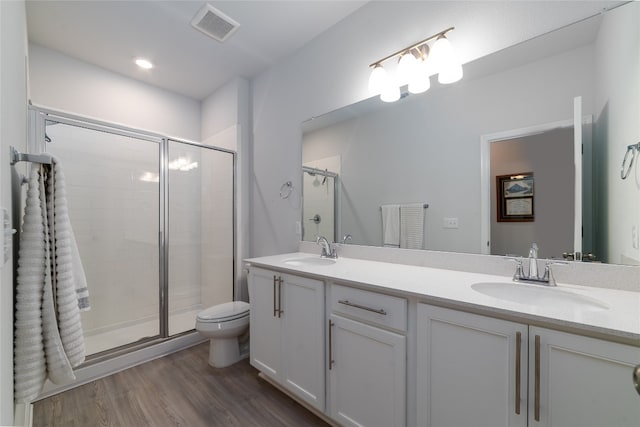 bathroom featuring hardwood / wood-style floors, walk in shower, vanity, and toilet