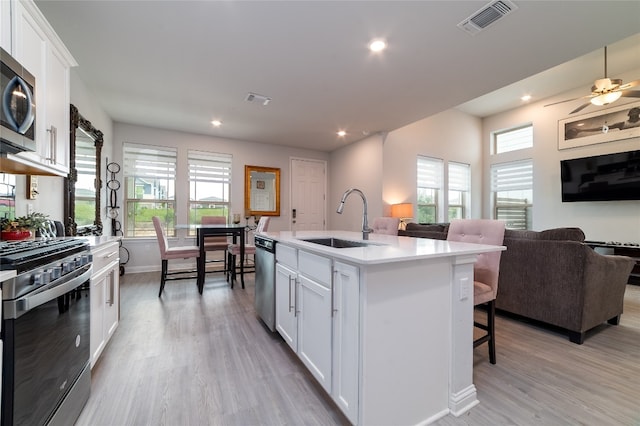 kitchen with white cabinetry, an island with sink, stainless steel appliances, ceiling fan, and sink