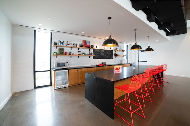 kitchen featuring wine cooler, hanging light fixtures, a kitchen island, a kitchen breakfast bar, and decorative backsplash