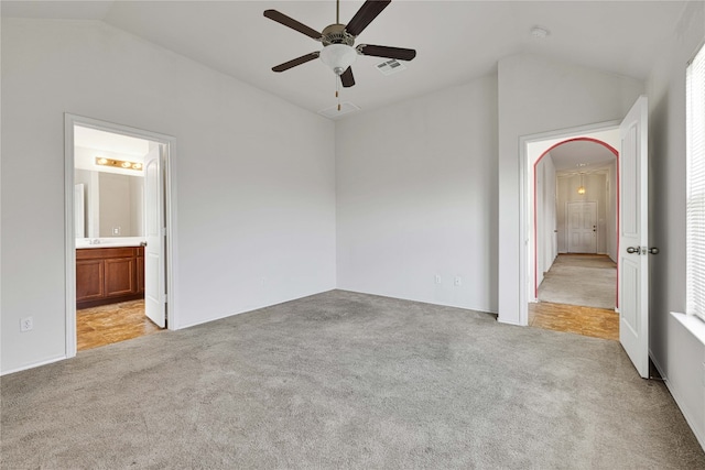 unfurnished bedroom featuring lofted ceiling, ensuite bath, light carpet, and ceiling fan