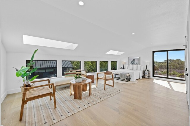 living room featuring lofted ceiling with skylight and light hardwood / wood-style flooring