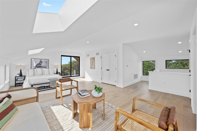 living room featuring light hardwood / wood-style flooring and vaulted ceiling with skylight