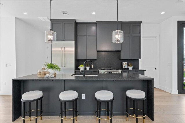 kitchen with backsplash, stainless steel appliances, light hardwood / wood-style flooring, decorative light fixtures, and sink