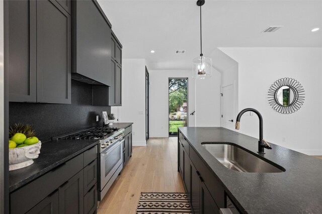 kitchen with light hardwood / wood-style floors, tasteful backsplash, sink, decorative light fixtures, and high end range