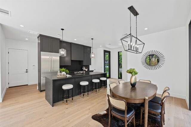 dining room with light wood-type flooring, a chandelier, and sink