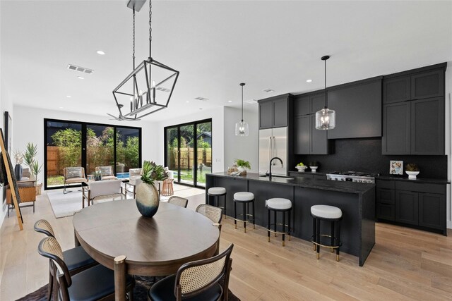 dining space with an inviting chandelier, sink, and light hardwood / wood-style flooring