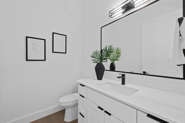 bathroom with vanity, toilet, and hardwood / wood-style flooring