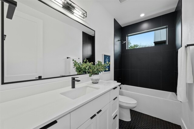 full bathroom with tile patterned flooring, tiled shower / bath combo, vanity, and toilet