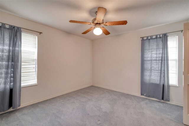 carpeted empty room with ceiling fan and a wealth of natural light