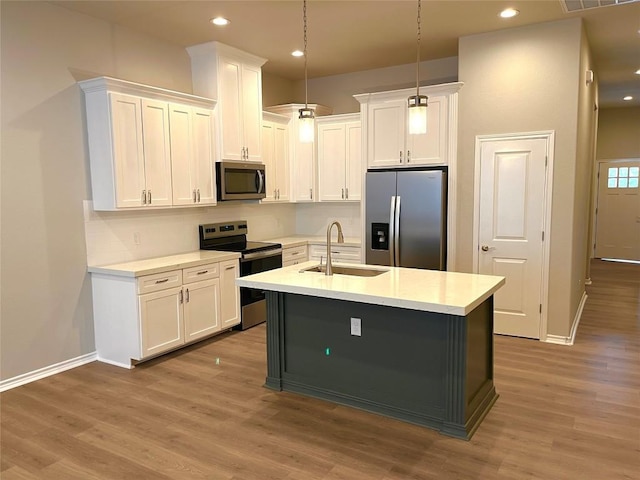 kitchen with appliances with stainless steel finishes, sink, wood-type flooring, decorative light fixtures, and white cabinets