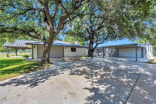 single story home featuring a front yard, an outdoor structure, a garage, and a carport