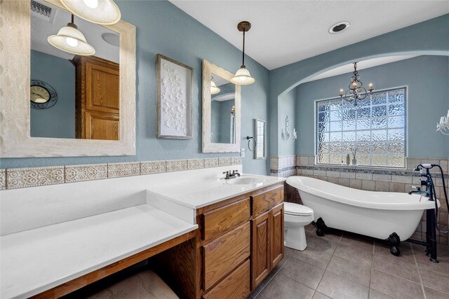 bathroom featuring vanity, tile patterned flooring, toilet, a washtub, and a notable chandelier