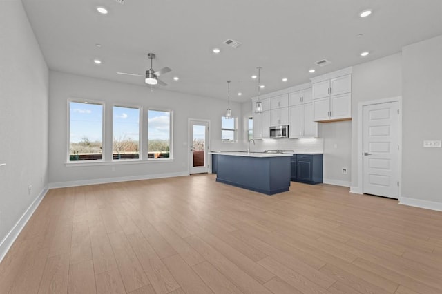 kitchen featuring sink, light hardwood / wood-style flooring, blue cabinetry, white cabinets, and decorative light fixtures