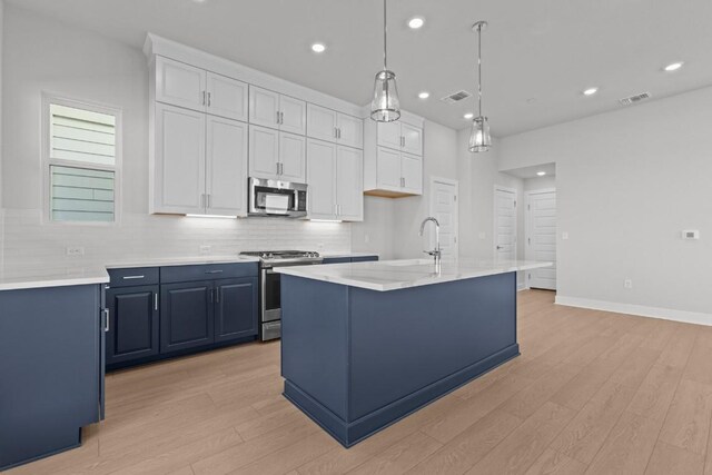 kitchen featuring white cabinetry, hanging light fixtures, an island with sink, and appliances with stainless steel finishes