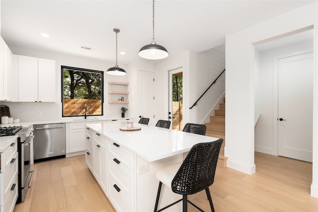 kitchen with white cabinets, plenty of natural light, a kitchen island, and stainless steel appliances