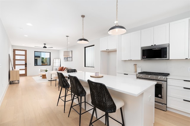 kitchen featuring a center island, white cabinets, stainless steel appliances, and light hardwood / wood-style flooring