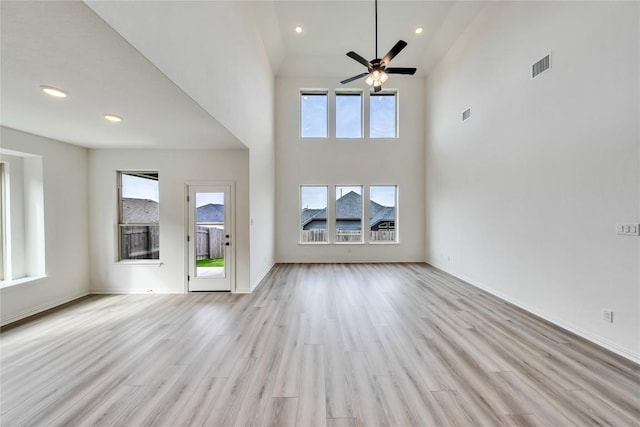 unfurnished living room with ceiling fan, light wood-type flooring, and high vaulted ceiling