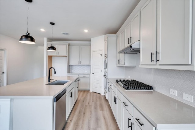 kitchen with white cabinets, appliances with stainless steel finishes, sink, and an island with sink