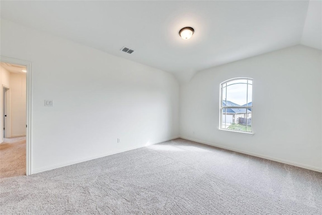 carpeted spare room with vaulted ceiling