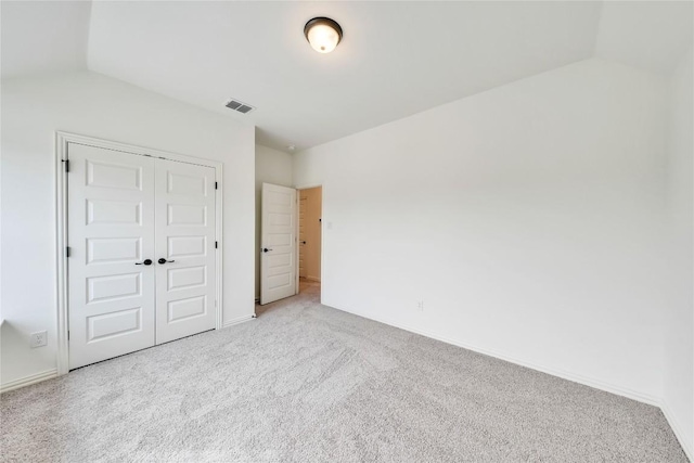 unfurnished bedroom with lofted ceiling, light carpet, and a closet