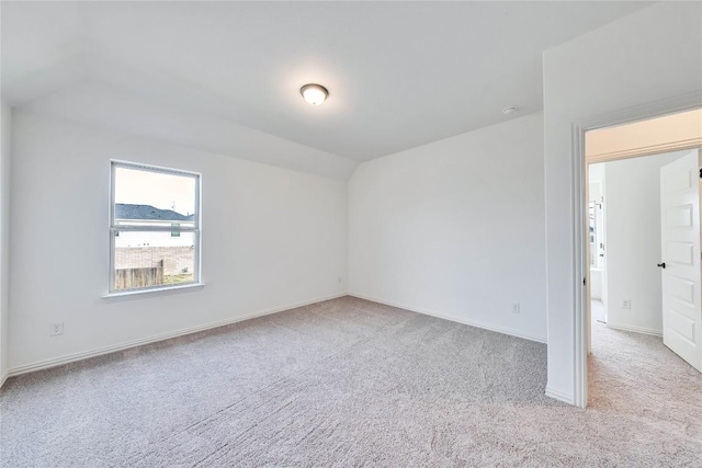 carpeted spare room featuring vaulted ceiling