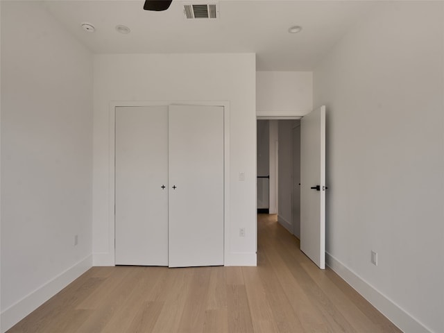 unfurnished bedroom featuring light wood-style flooring, a closet, visible vents, and baseboards