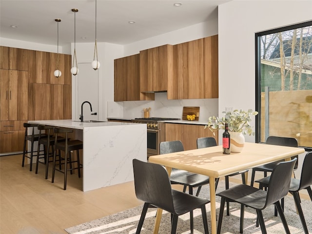 kitchen featuring high end stove, modern cabinets, brown cabinetry, and a sink