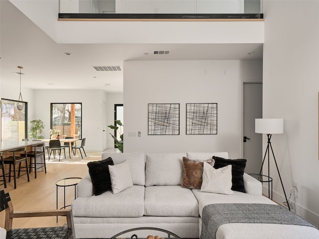 living area featuring baseboards, visible vents, and wood finished floors