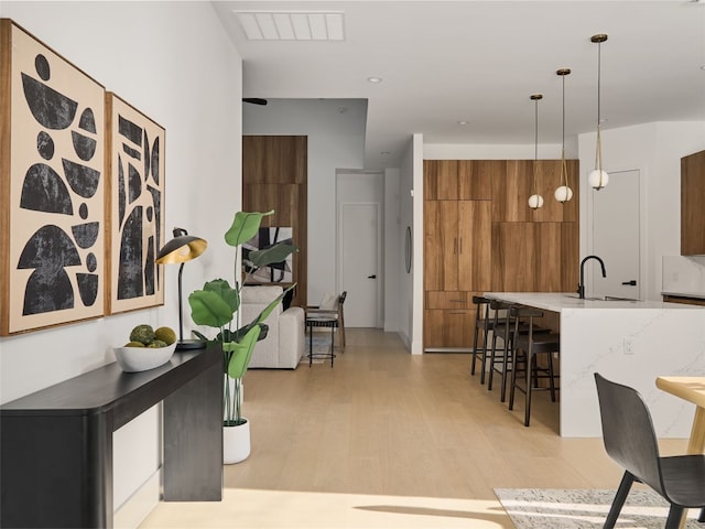 interior space featuring light wood-style flooring, visible vents, and a sink