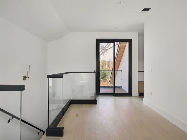 interior space featuring lofted ceiling, visible vents, baseboards, and wood finished floors