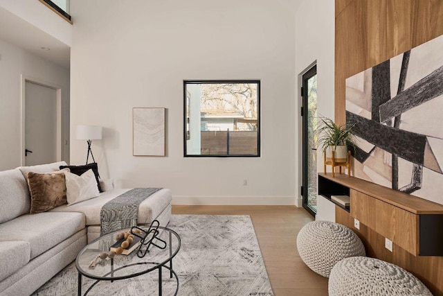 living room featuring baseboards, a high ceiling, and light wood finished floors