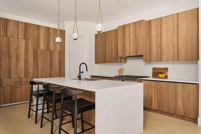 kitchen with modern cabinets, a breakfast bar area, brown cabinetry, and a sink