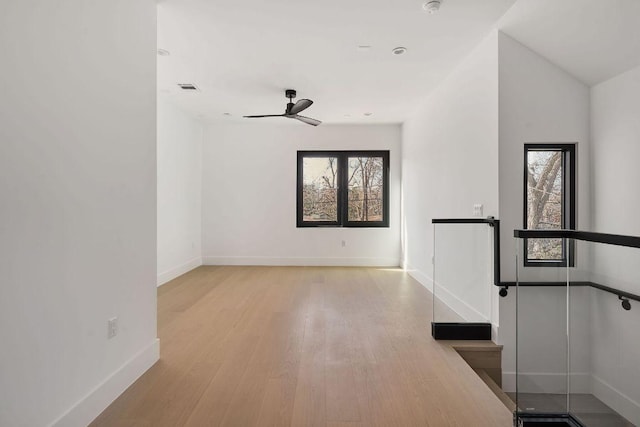 spare room featuring baseboards, wood finished floors, visible vents, and a healthy amount of sunlight