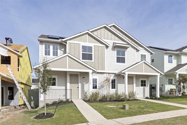 view of front facade featuring a front yard, a porch, and solar panels