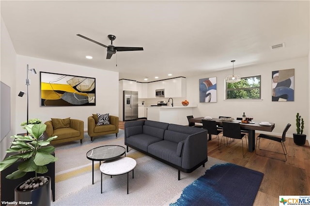 living room featuring ceiling fan, light wood-type flooring, and sink