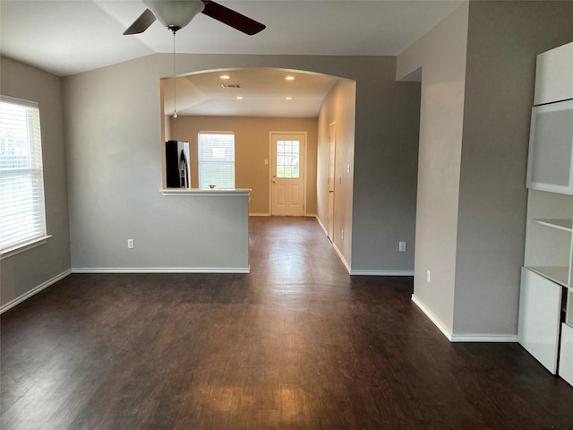 empty room with ceiling fan, dark hardwood / wood-style floors, and vaulted ceiling