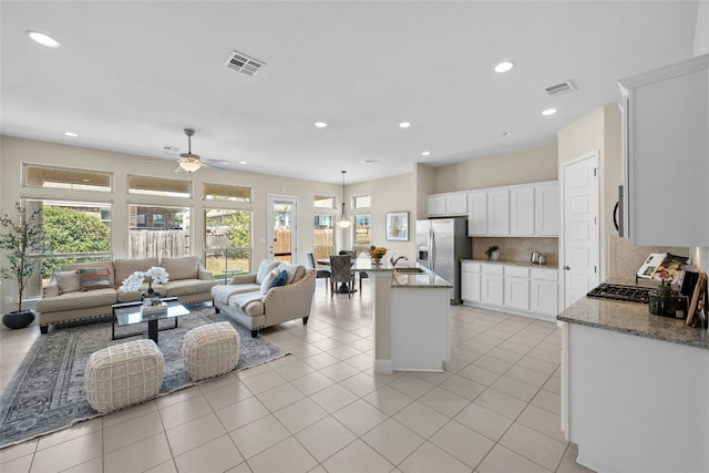 kitchen featuring backsplash, light stone countertops, ceiling fan, and white cabinets