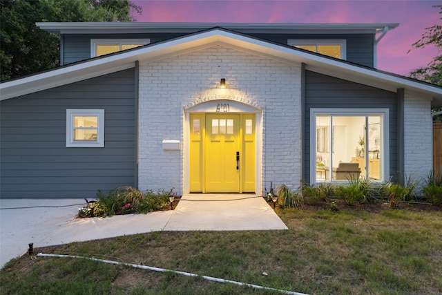 exterior entry at dusk featuring a yard