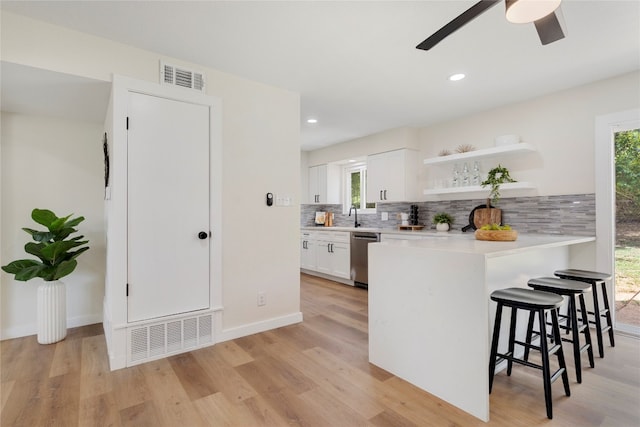 kitchen with dishwasher, tasteful backsplash, white cabinetry, light hardwood / wood-style flooring, and ceiling fan