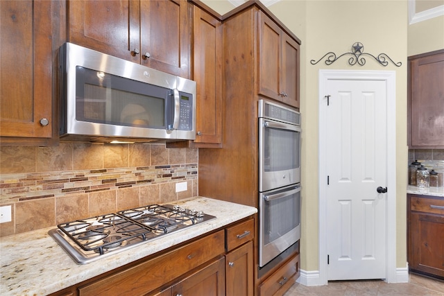 kitchen featuring backsplash, light stone countertops, crown molding, and stainless steel appliances