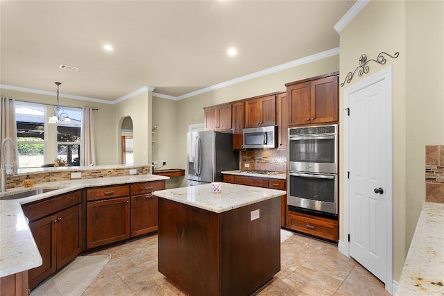 kitchen with tasteful backsplash, stainless steel appliances, sink, decorative light fixtures, and a center island